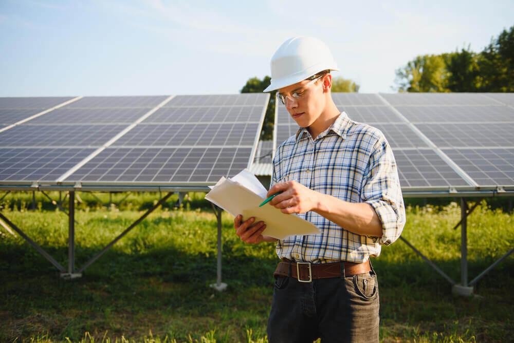 young engineer reviewing solar development paperwork behind pv solar system