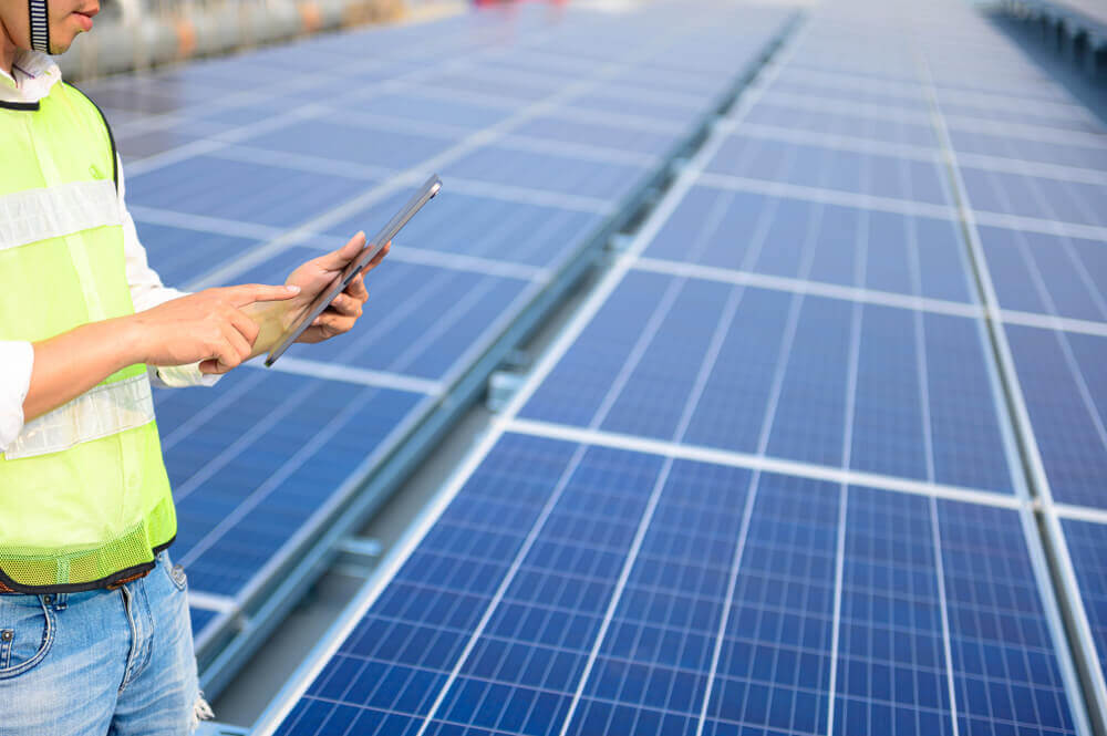solar panel technician inspecting grid with ipad