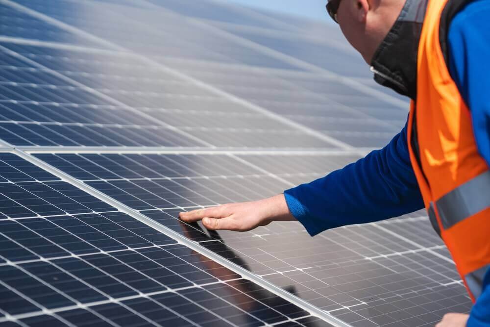 technician inspecting a solar panel surface with his hand