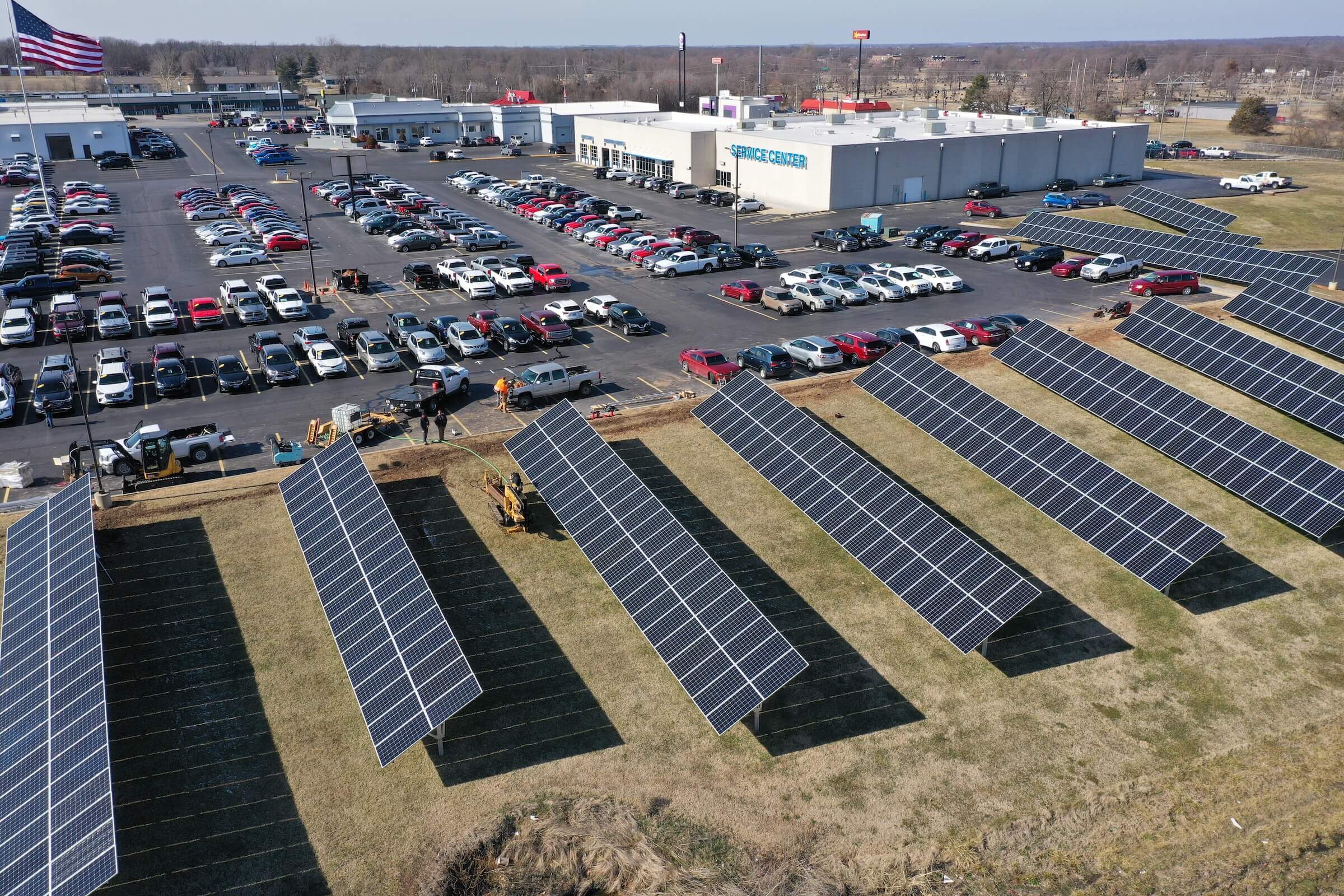 ground-mounted solar panel systems on a lawn next to parking lot