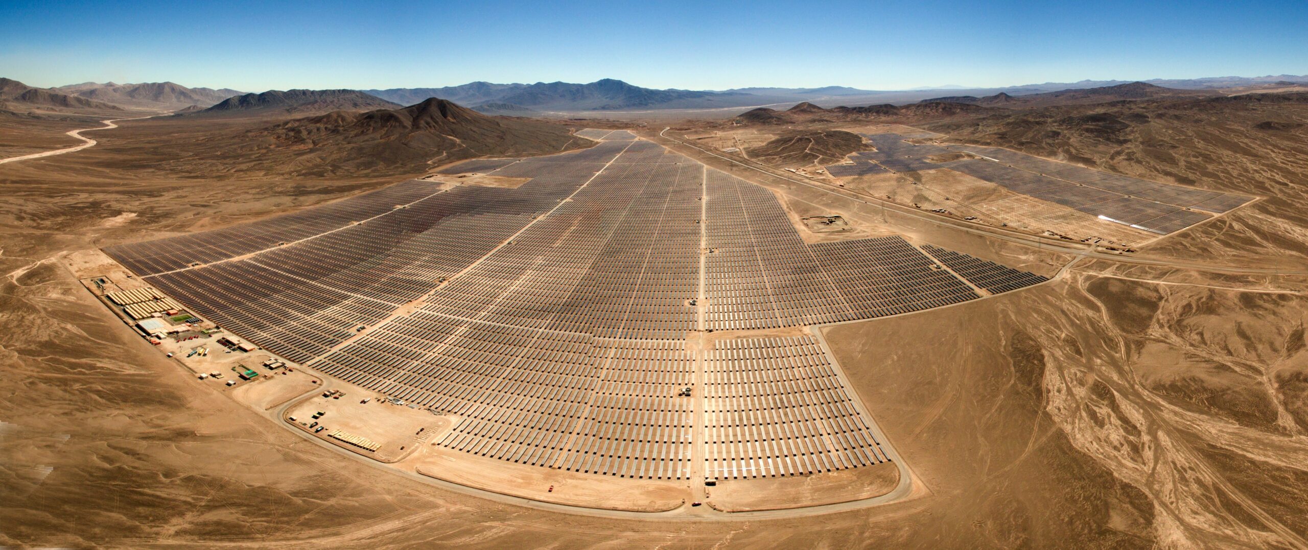 Aerial view of a large-scale solar farm in a desert landscape, highlighting the expansive nature of commercial solar installations.