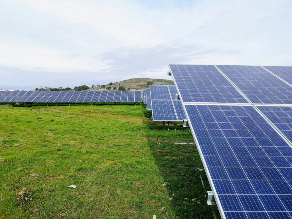 Solar panels in a green field under a cloudy sky in the Midwest, showcasing renewable energy in agricultural settings.