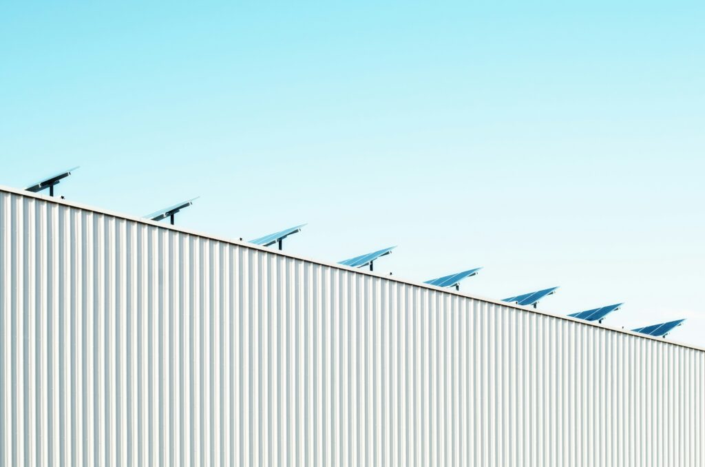 Solar panels mounted on the edge of a large industrial building against a clear blue sky, emphasizing the efficiency and space utilization of commercial solar panels.